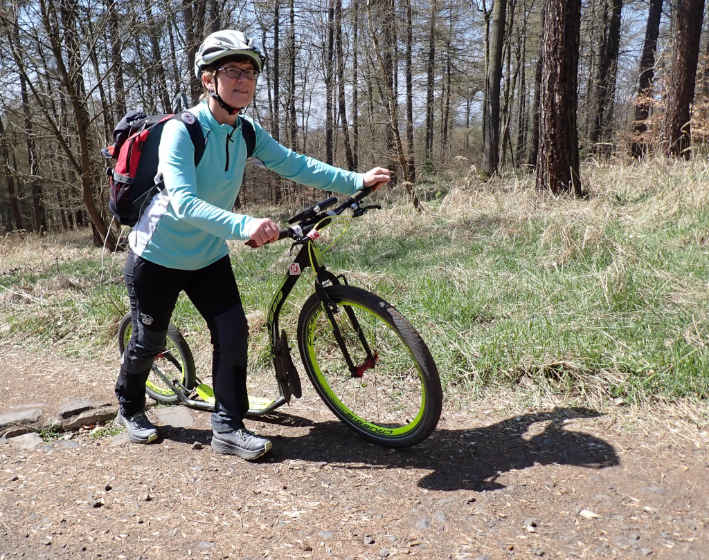Hana tlačí koloběžku po lesní svážnici k Dlouhému vrchu. 