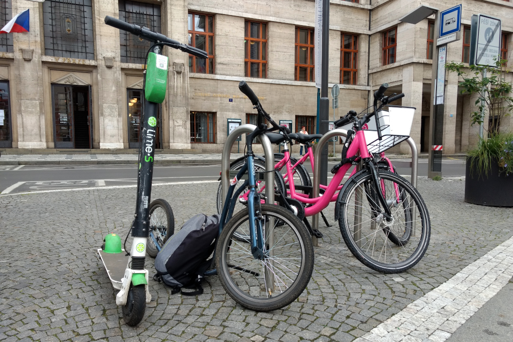 Před pražskou Městskou knihovnou zleva: elektrokoloběžka Lime, koloběžka Yedoo S2016, sdílená Ružová kola.