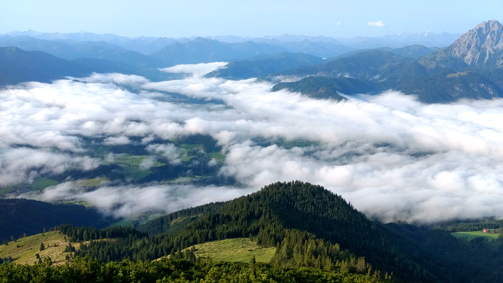 Tennengebirge. Pohled od chaty Werfenerhütte do údolí k Werfenweng, vpravo dole je vidět horský statek Mahdegg, vzadu vpravo vyčnívá masiv Hochkönig, v údolí pod mraky teče Salzach.
