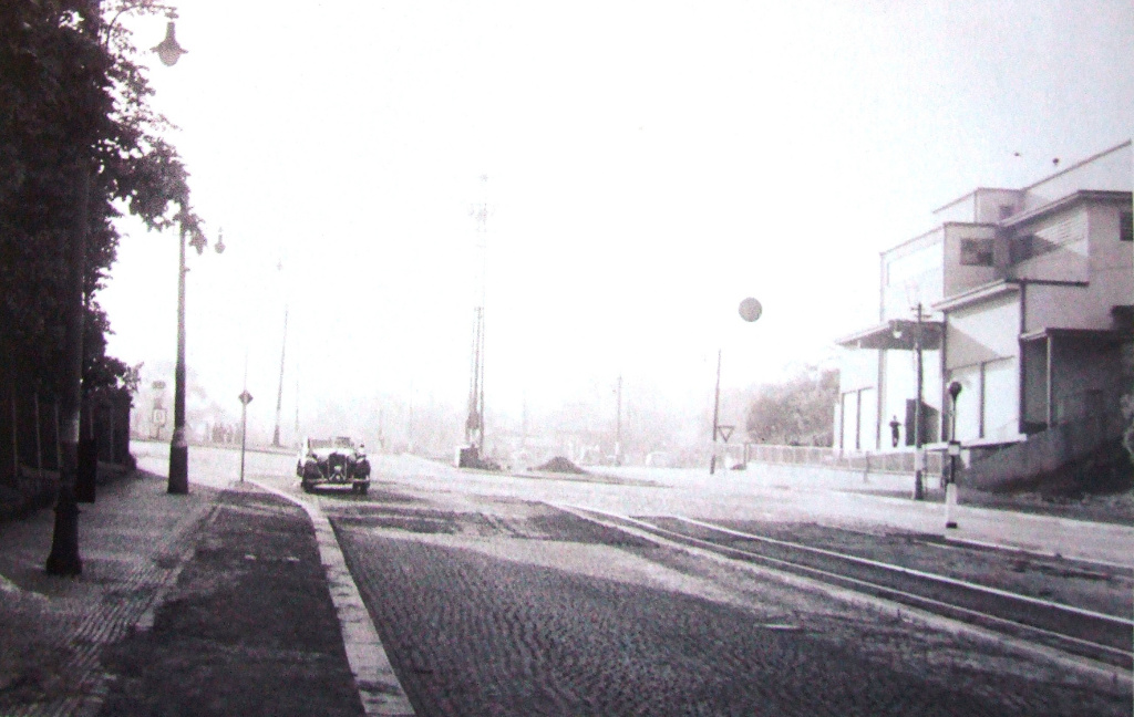 Praha. Ulice v Holešovičkách. Pohled směrem od Trojského mostu na sever. Budova vlevo, bývalá elektrostanice, je pořád svědkem atentátu. Nalevo se napojuje Zenklova, po které přijel Heydrich, původně byla ale posunuta více na sever.
