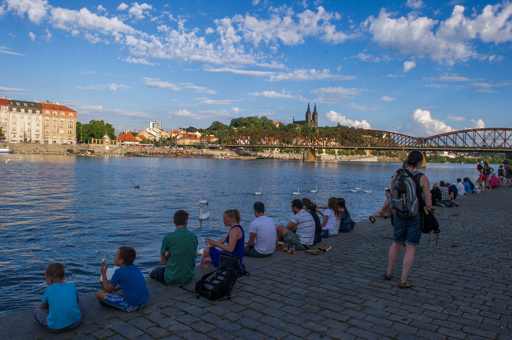 Lidé sedící na Smíchovské náplavce hledí na Vyšehrad.