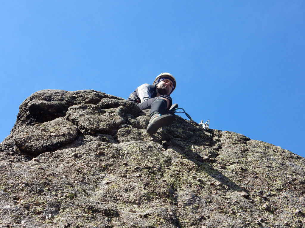 Petr sedí u slaňovacího kruhu na vrcholu skalní věže Stojka. Ořešník, Jizerské hory.