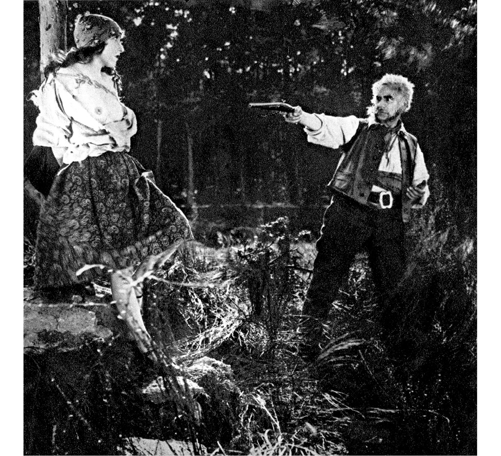 Loupežníci na Chlumu. Záběr ze ztraceného němého filmu z roku 1926 ukazuje Jana Vávru, který míří na obnažené poprsí své herecké dcery. Režie Miloš Hajský.