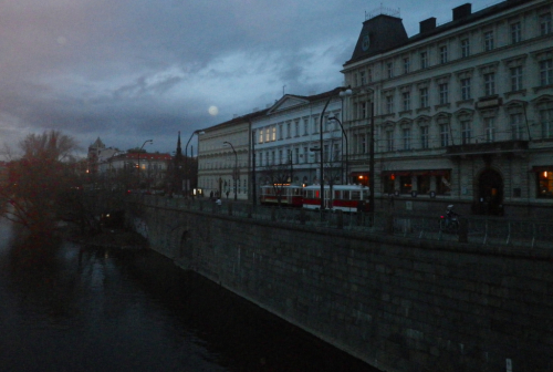 Praha. Historická tramvaj projíždí po Smetanově nábřeží za soumraku.