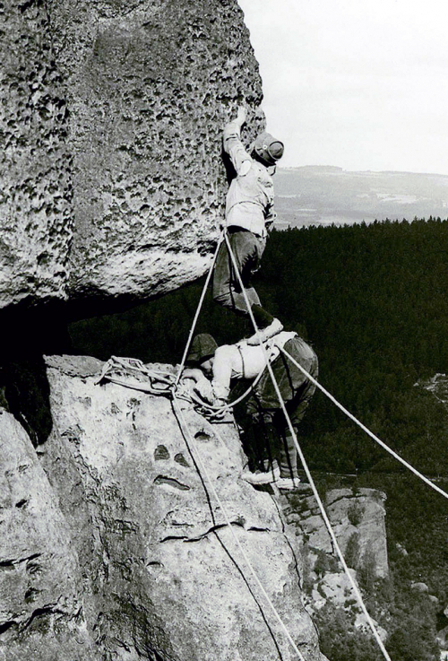 Lezci v Českosaském Švýcarsku kolem roku 1915. Konopná lana odvážně navázaná kolem pasu, obuv s plstěnou podešví. Na obrázku zvláštní technika lezení zvaná stavění. 