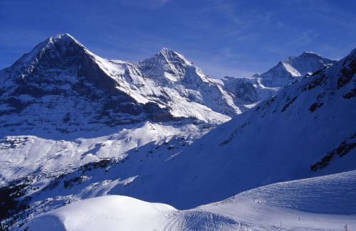 Eiger (3970 m). Severní stěna. Zleva přichází hřeben Mittellegi. Vzadu uprostřed Mönch a vpravo Jungfrau.